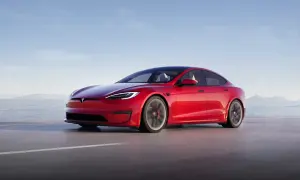 Roter Tesla Model S fährt auf einer Straße am Meer entlang.